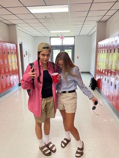 two young women standing next to each other in a hallway with lockers behind them