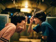 two young boys are looking at each other through their eyes with scissors in front of them