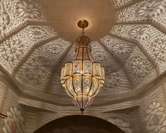 a chandelier hanging from the ceiling in a room with intricate designs on it