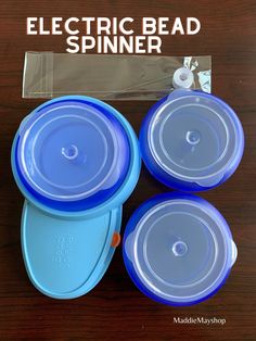 three electric bead spinners sitting next to each other on a wooden table with plastic packaging