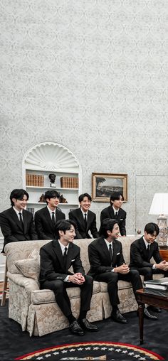 a group of men in suits sitting on couches