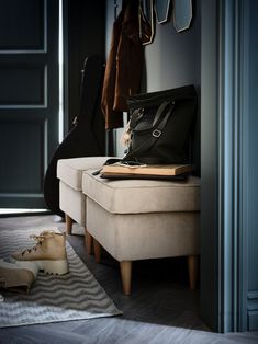 an open suitcase sitting on top of a bench next to a pair of shoes and coat rack