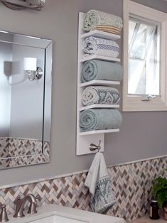 a white sink sitting under a bathroom mirror next to a shelf filled with folded towels