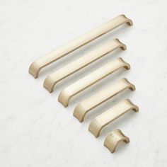 five brass handles on a white marble surface