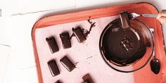 a person cutting chocolate with a knife and some other items in the tray behind them