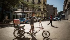 a man riding a bike with a baby carriage attached to it's front wheel