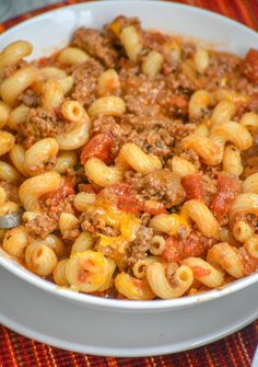 a white bowl filled with pasta and meat in tomato sauce on top of a table