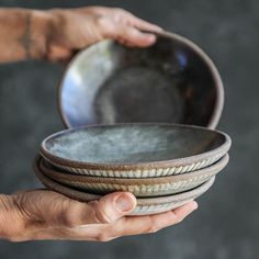 a person holding three plates in their hands, one is gray and the other is brown