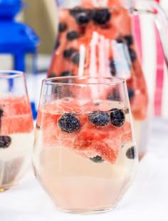 two glasses filled with ice and berries on top of a table