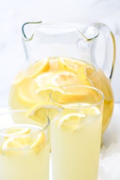 two glasses filled with lemonade next to a pitcher