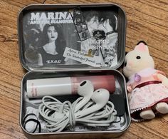 an open tin with earbuds and a stuffed animal in it