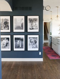 black and white photographs hanging on the wall in a kitchen with wood flooring below