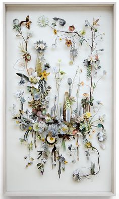 an art piece with flowers and plants on it's side in a white frame