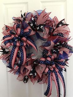 a patriotic wreath with red, white and blue ribbons hanging on the front door for memorial day