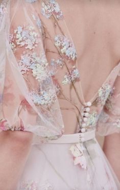 the back of a woman's wedding dress with flowers on it and sheer fabric