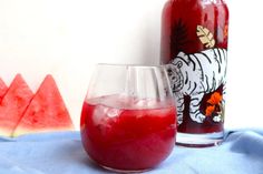 a glass filled with watermelon juice next to a bottle