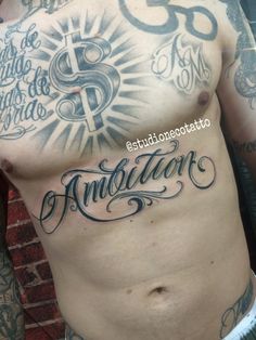 a man's chest with tattoos and lettering on his chest, in front of a brick wall