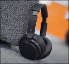 a pair of headphones sitting on top of a gray couch next to a pillow