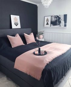 a black and pink bedroom with chandelier above the bed, artwork on the wall