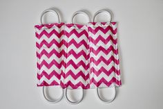 three pink and white chevroned paper towels are hanging on two pairs of scissors