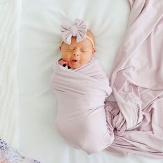 a baby wrapped in a blanket sleeping on top of a bed