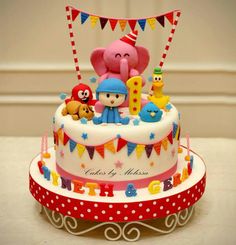 a birthday cake with an elephant and other toys on the top is decorated in red, white, and blue