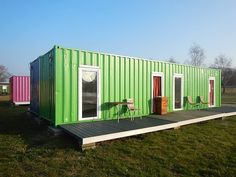 a green shipping container sitting on top of a grass covered field next to a picnic table