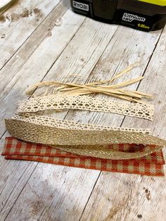 three rolls of lace on top of a wooden table next to a toolbox and other crafting supplies