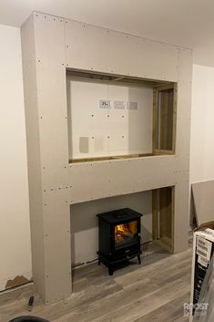 a room that is being built with some wood in it and a stove inside the wall