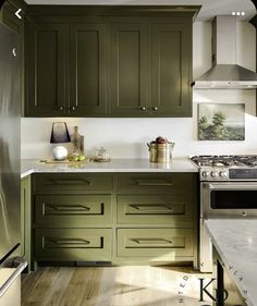 a kitchen with green cabinets and white counter tops, an oven and stove top in the center