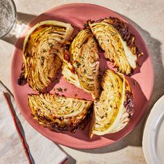 a pink plate topped with sliced artichokes on top of a table