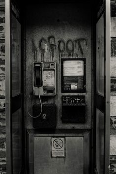 an old fashioned payphone with graffiti on it's side and the door open