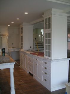 a large kitchen with white cabinets and wood floors