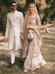 a man and woman dressed in wedding attire standing next to each other on the grass