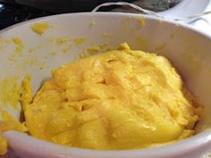 a white bowl filled with yellow food on top of a counter next to a stove