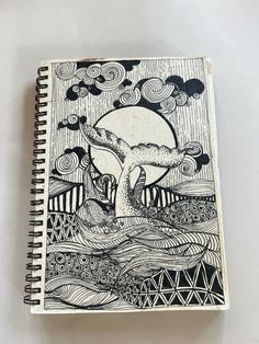 a spiral notebook with an image of a whale in the ocean and waves on it