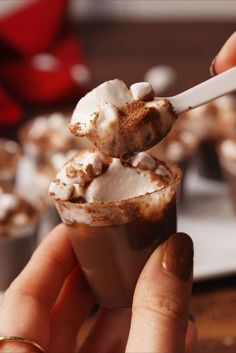 a person holding a spoon with some food in it's hand while eating something out of a cup