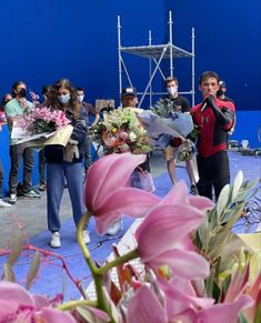 a group of people standing on top of a stage holding bouquets of flowers in front of them