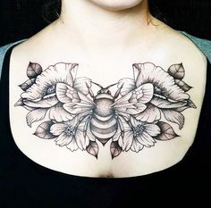 a woman's chest with flowers and a bee tattoo on her left side breast