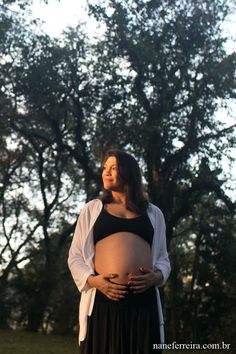 a pregnant woman standing in front of a tree