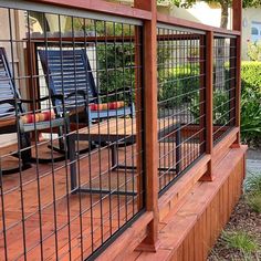 a wooden deck with two chairs on it and a fenced in area next to it