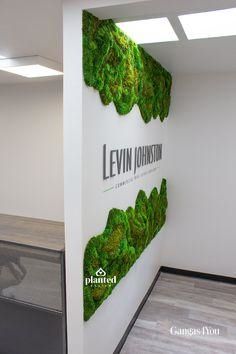 an office cubicle with green plants on the wall, and a sign that says levin johnson