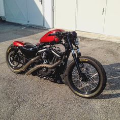 a red and black motorcycle parked in front of a garage