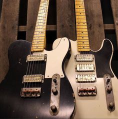 two electric guitars sitting side by side in a wooden box, one is white and the other is black