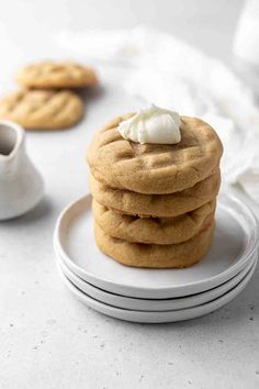 a stack of cookies with marshmallows on top and two white cups in the background