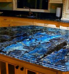 a kitchen counter top with blue and black marble on it in front of an oven