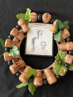 a wreath made out of wine corks with leaves and berries around it on a black background