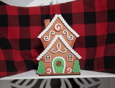 a gingerbread house on a red and black checkered pillow