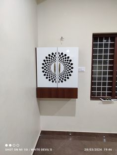 a white wall mounted cabinet next to a window in a room with tile flooring