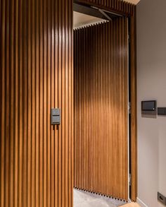 an open wooden door in a room with white walls and wood slats on the wall